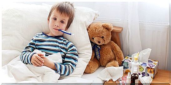 Boy lying in bed with a thermometer in his mouth.