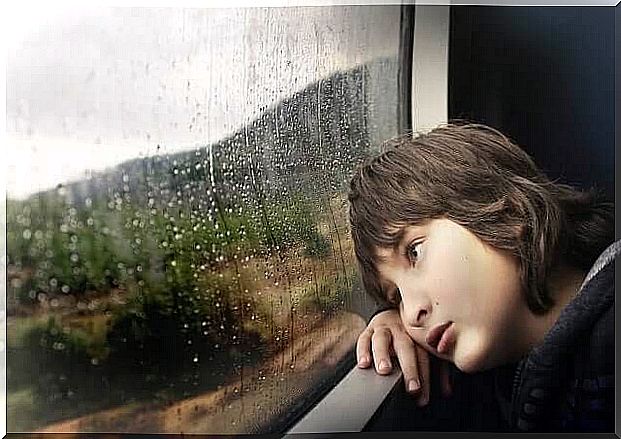 Tired child looking at the rain in the window