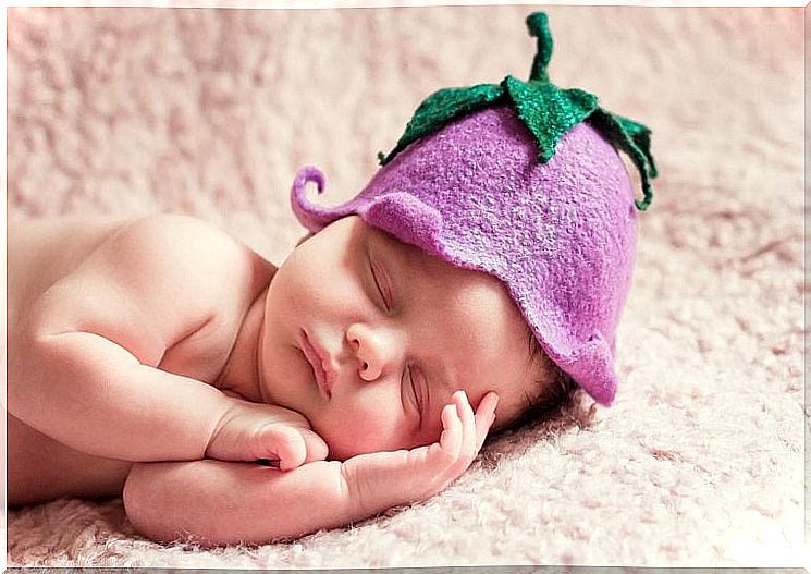 newborn sleeping with a flower on his head