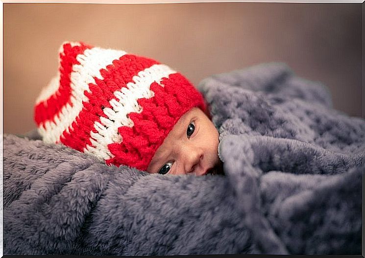 newborn with a hat on his head and a blanket from the cold